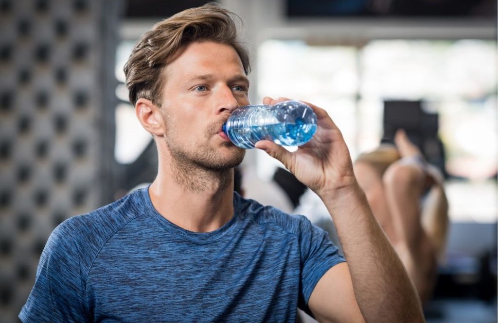 sportlicher Mann trinkt Magnesium Flasche beim Sport