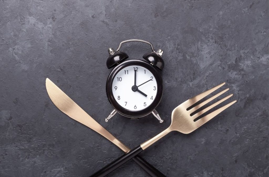 Uhr mit gekreuztem Besteck symbolisch für Intervallfasten