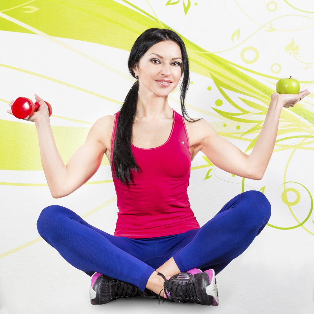 Fitnesssport dargestellt von Autorin Oxana Hegel mit Hantel und Apfel