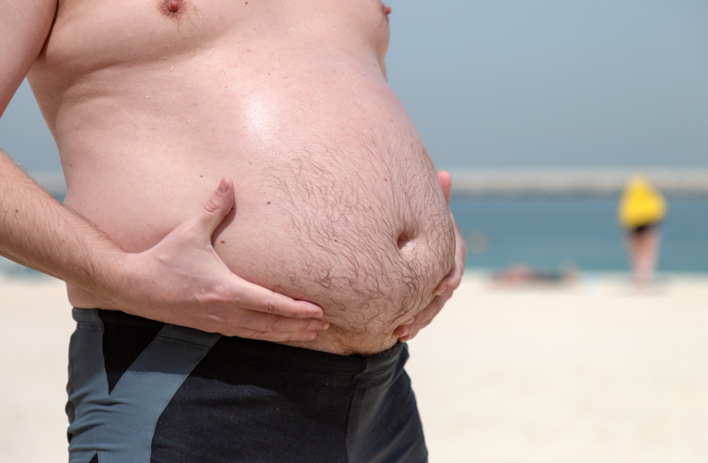 dicker Männerbauch am Strand symbolisch für Abnehmspritze Wegovy