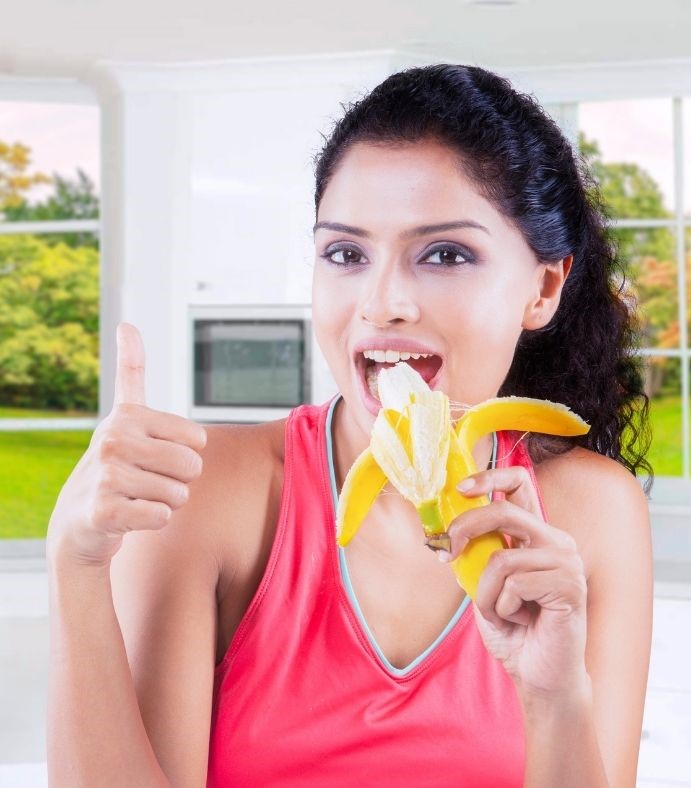 Bananen-Diät dargestellt von junger Frau mit Banane zum Frühstück