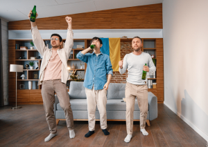 Drei Männer trinken Bier zum Fußball symbolisch für Bierbauch