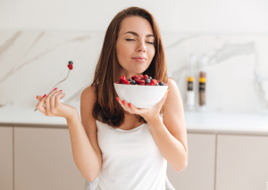 Frau isst Schüssel Beeren und beugt so Haarausfall durch Vitaminmangel vor