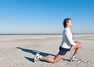 Hüftbeuger dehnen am Strand von einem Mann gezeigt