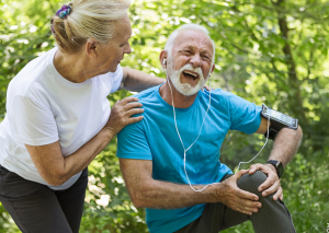 chronische Schmerzen in Patellasehne dargestellt von älterem Sportler mit Frau bei Joggen
