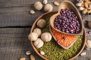 pflanzliches Eiweiß dargestellt von Bohnen und Erbsen auf einem Teller mit Nüssen