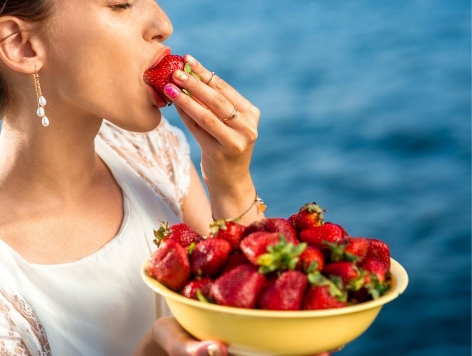Volumetrics-Diät symbolisiert von Frau die viele Erdbeeren isst