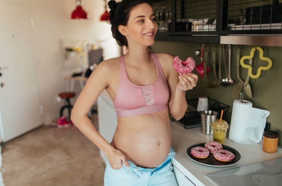 Heißhungerattacken während Schwangerschaft normal, dargestellt von Schwangeren beim Naschen